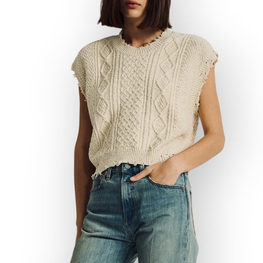 Ygreque Denimist ecru cable knit sleeveless boyfriend sweater with distressed edges worn by a woman with blue jeans