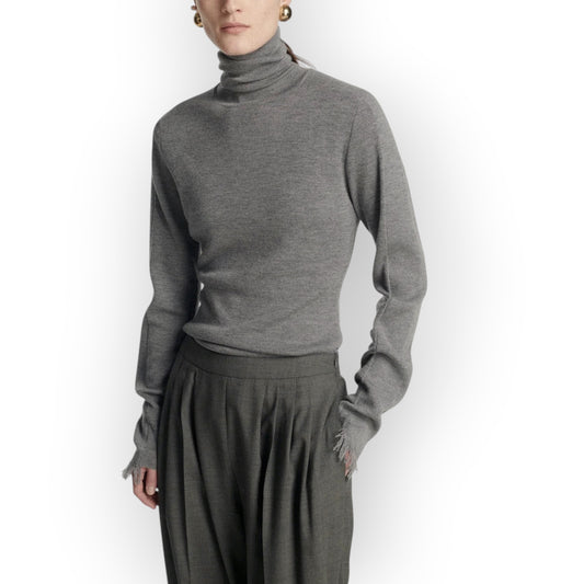 Model wearing a grey Frenken merino wool turtleneck sweater with slim fit and delicate fringe details at the cuffs.